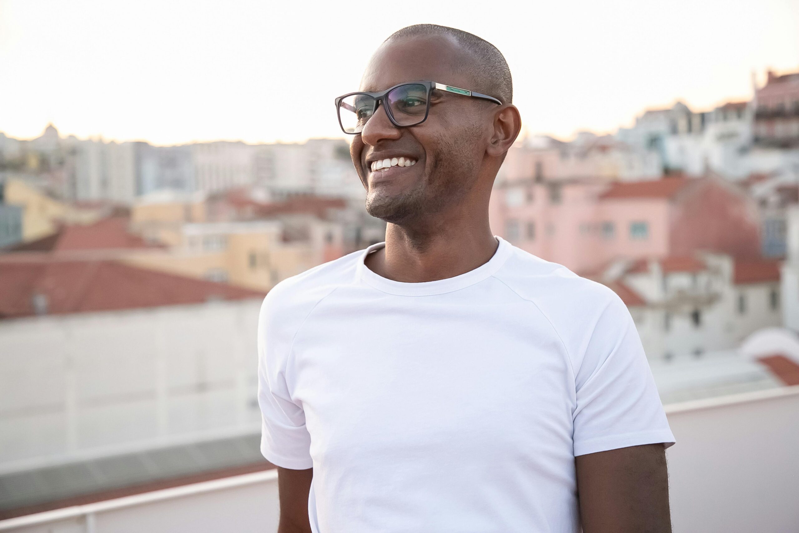 testimonial African American man smiling in white shirt with cityscape backdrop.